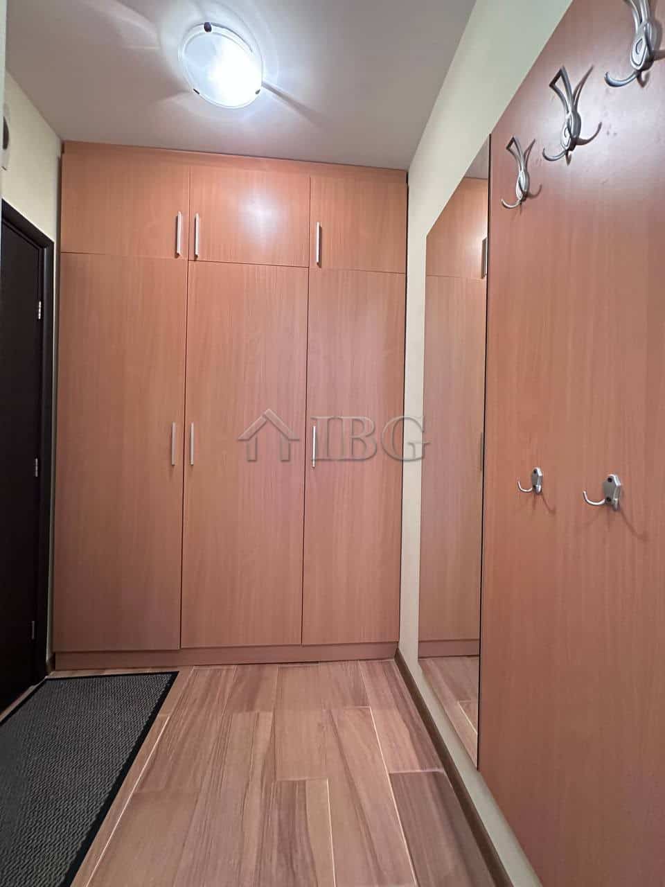 Interior view of a 1-bedroom apartment in Ravda with wooden wardrobes and hallway hooks.