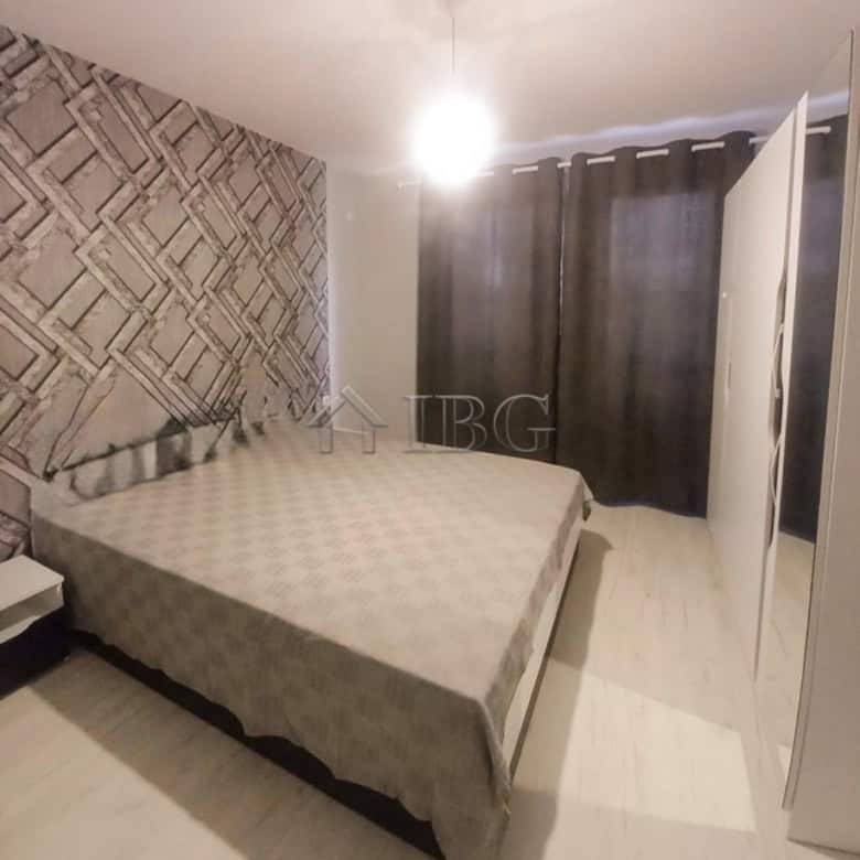 Furnished bedroom with a double bed, modern decor, and dark curtains in a central Ruse apartment.