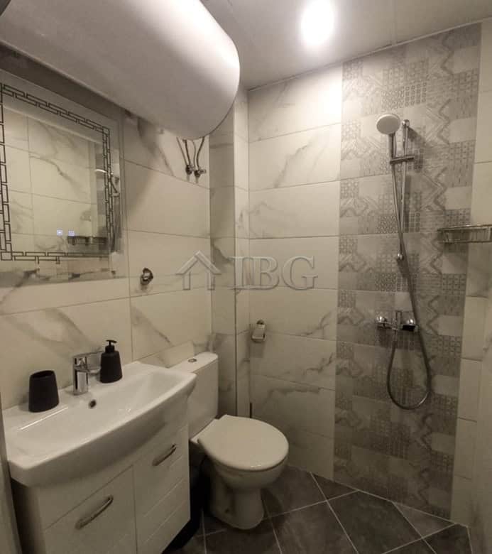 Compact bathroom with shower, toilet, and sink in a furnished apartment in Ruse city center.