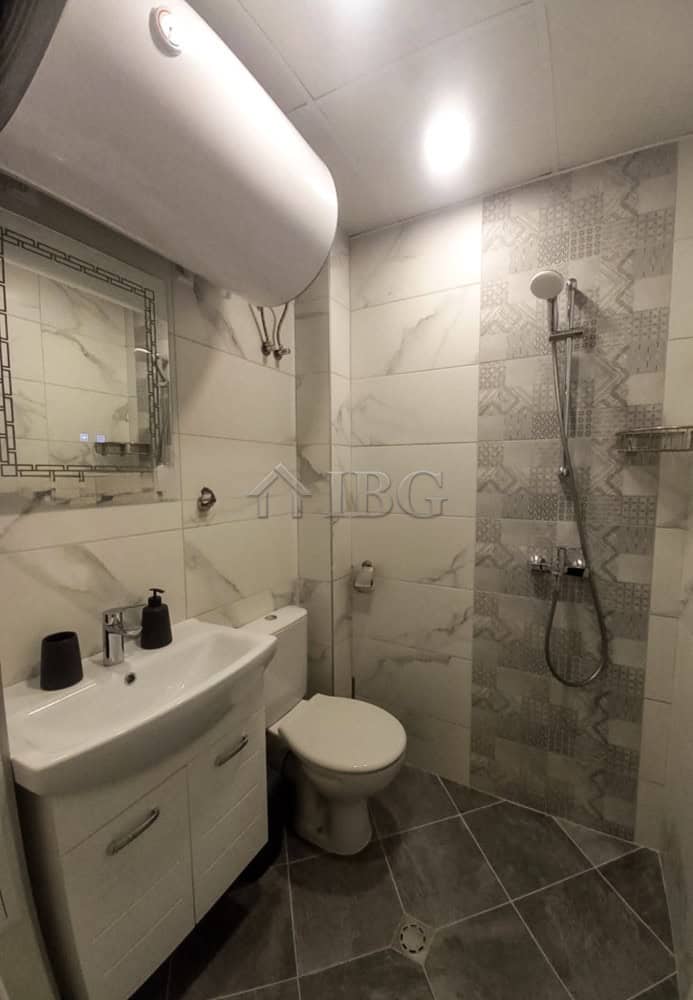 Compact bathroom with shower, toilet, and sink in a furnished apartment in Ruse city center.