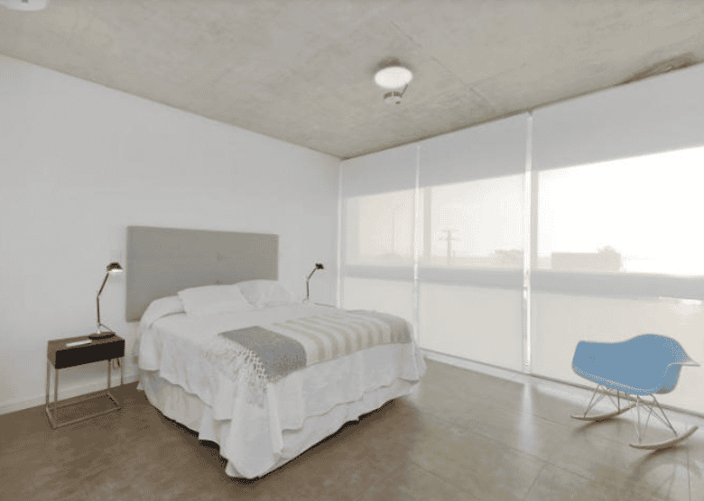 Spacious bedroom featuring large windows, white walls, and contemporary furniture.