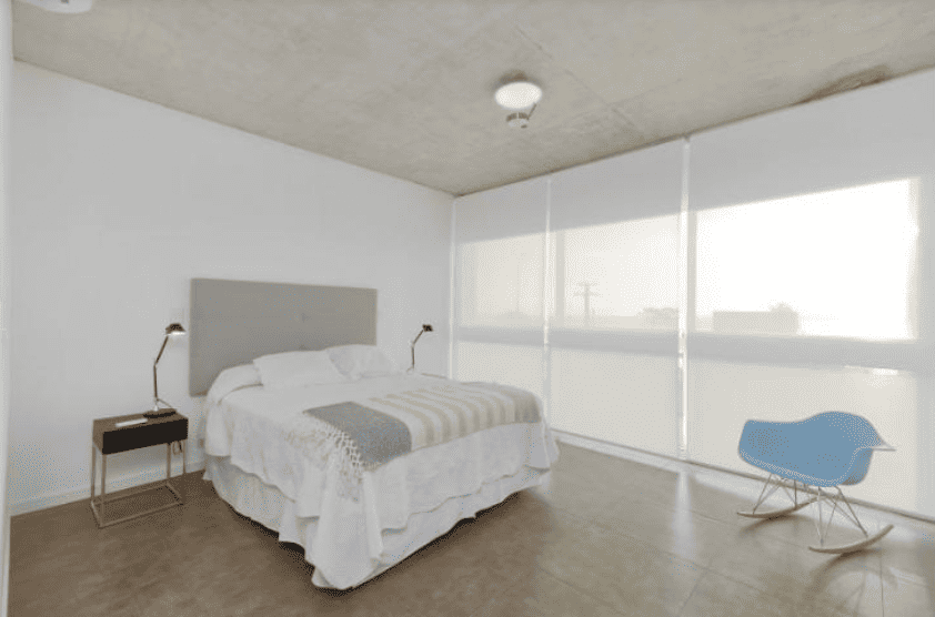Spacious bedroom featuring large windows, white walls, and contemporary furniture.
