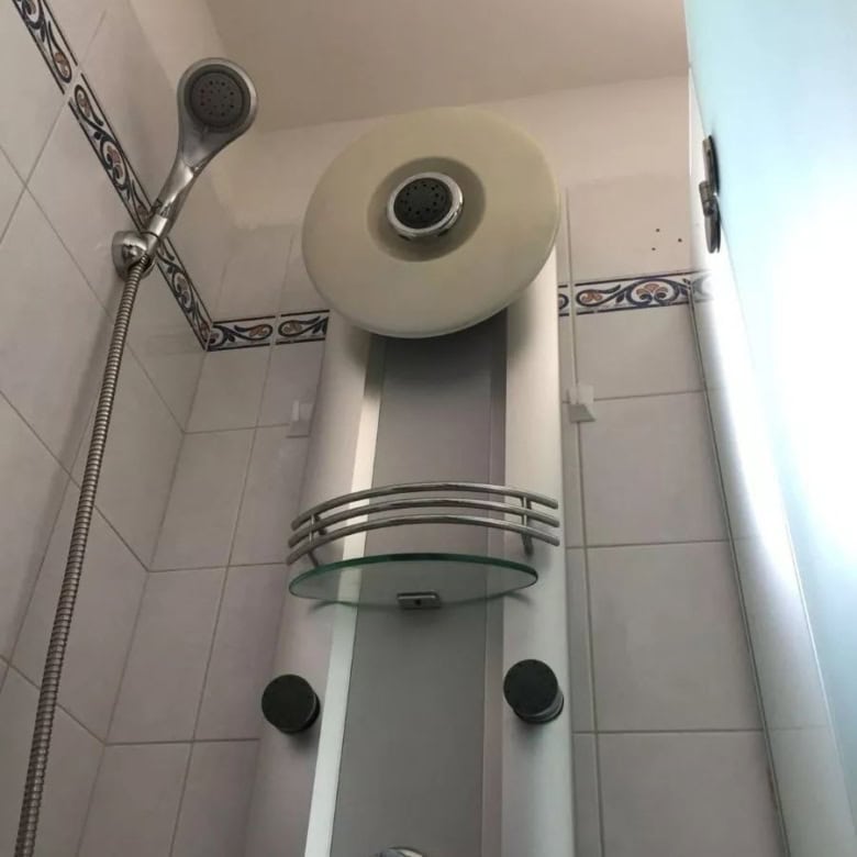 Electric water heater in a small bathroom with shower head.