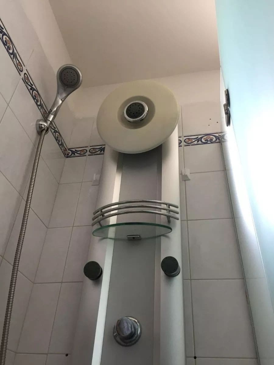 Electric water heater in a small bathroom with shower head.