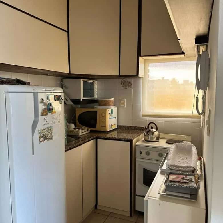 Compact kitchen with white cabinets and appliances in Punta del Este property.