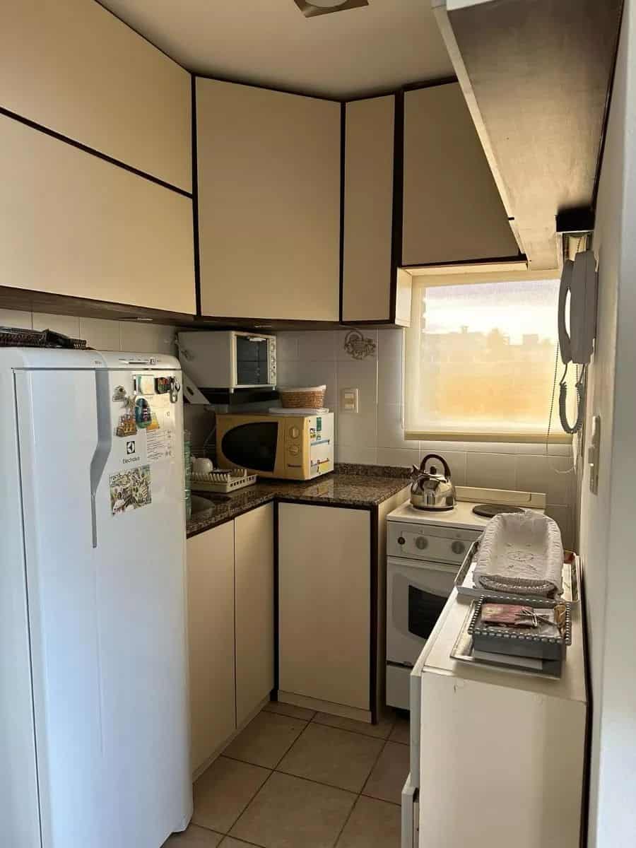 Compact kitchen with white cabinets and appliances in Punta del Este property.