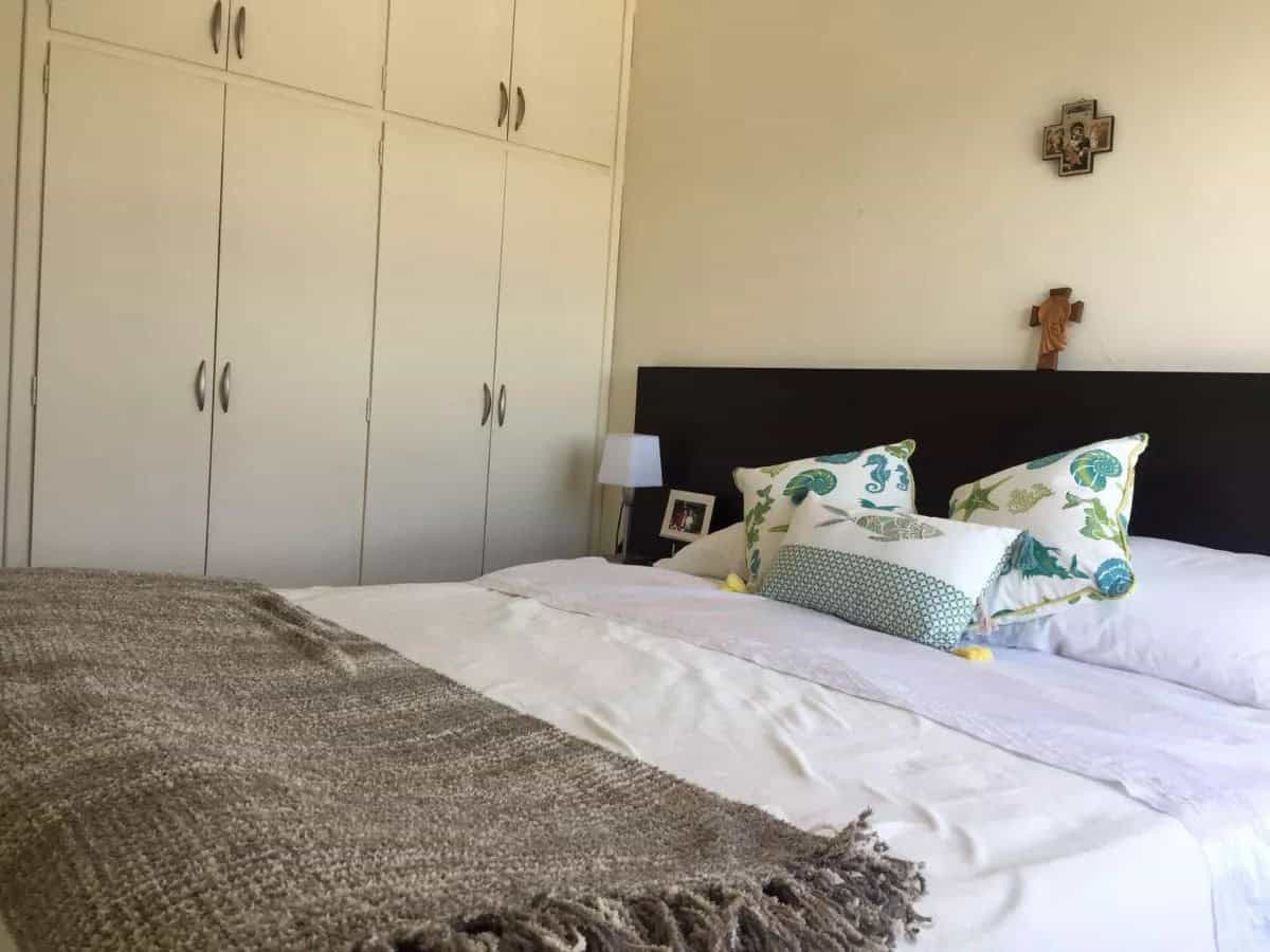 Spacious bedroom featuring a large bed, decorative pillows, and wall art in a coastal apartment.
