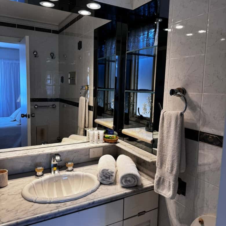 Bathroom with marble vanity, towels, and large mirror in Punta del Este.
