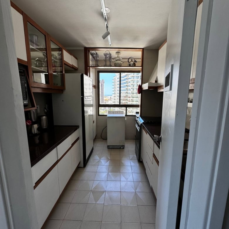 Spacious kitchen with white cabinets, appliances, and a view of the city skyline.
