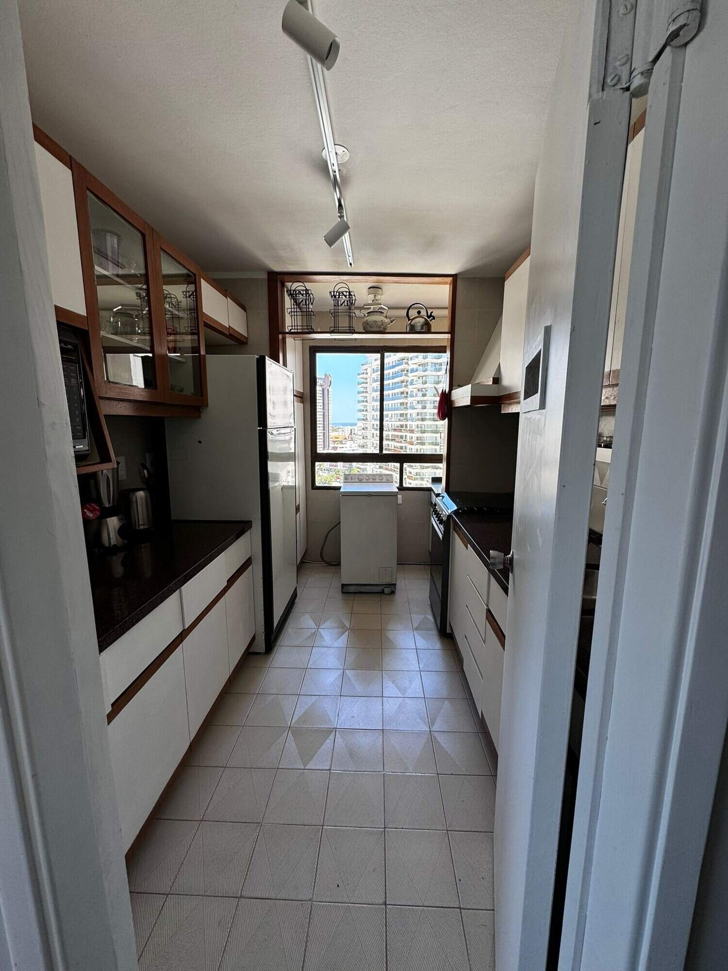 Spacious kitchen with white cabinets, appliances, and a view of the city skyline.