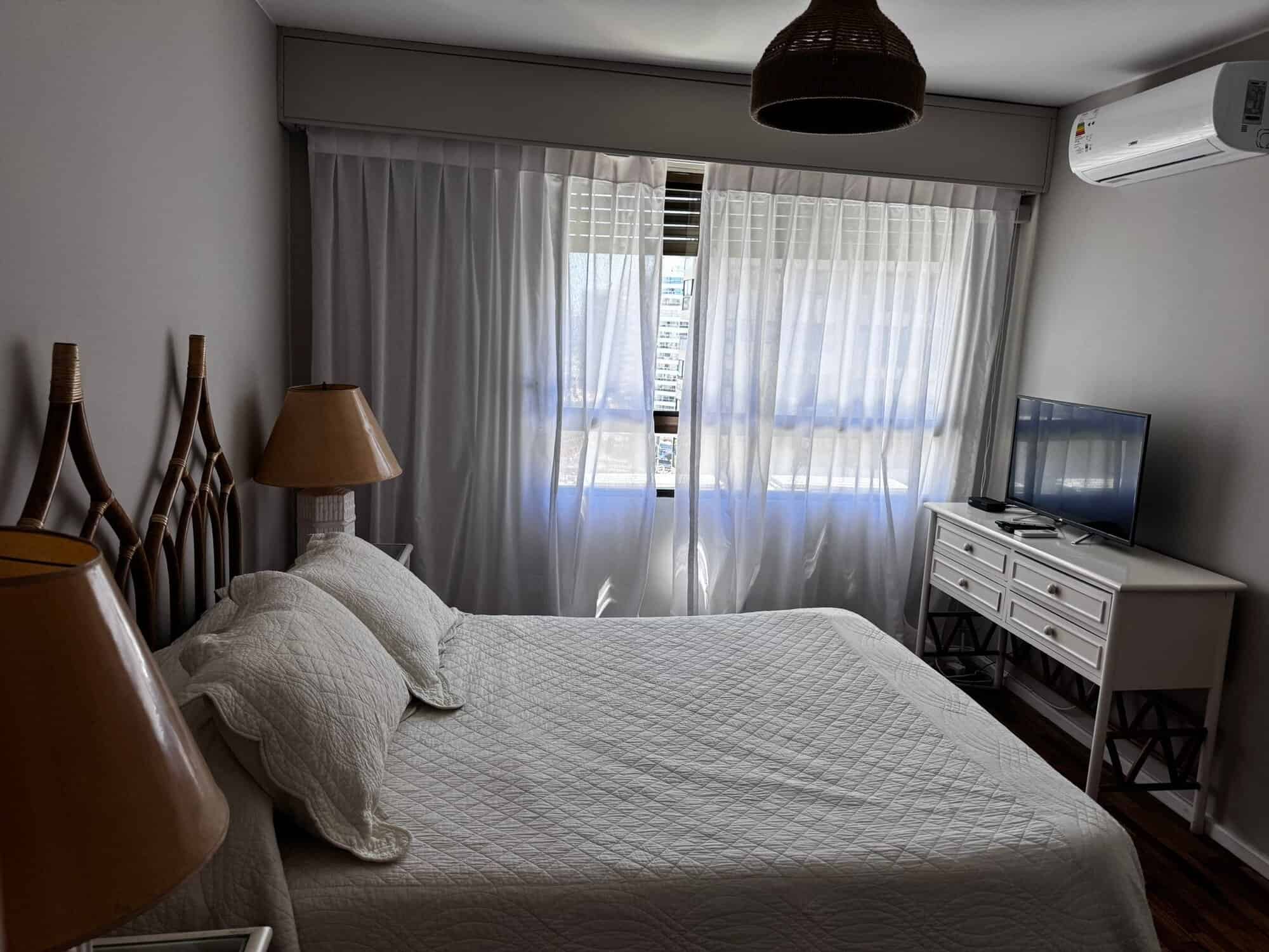 Bright bedroom with large window and air conditioning.