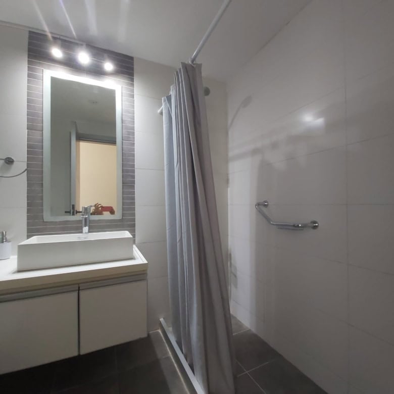 Bright bathroom with sink, mirror, and shower area in La Pastora, Punta del Este.