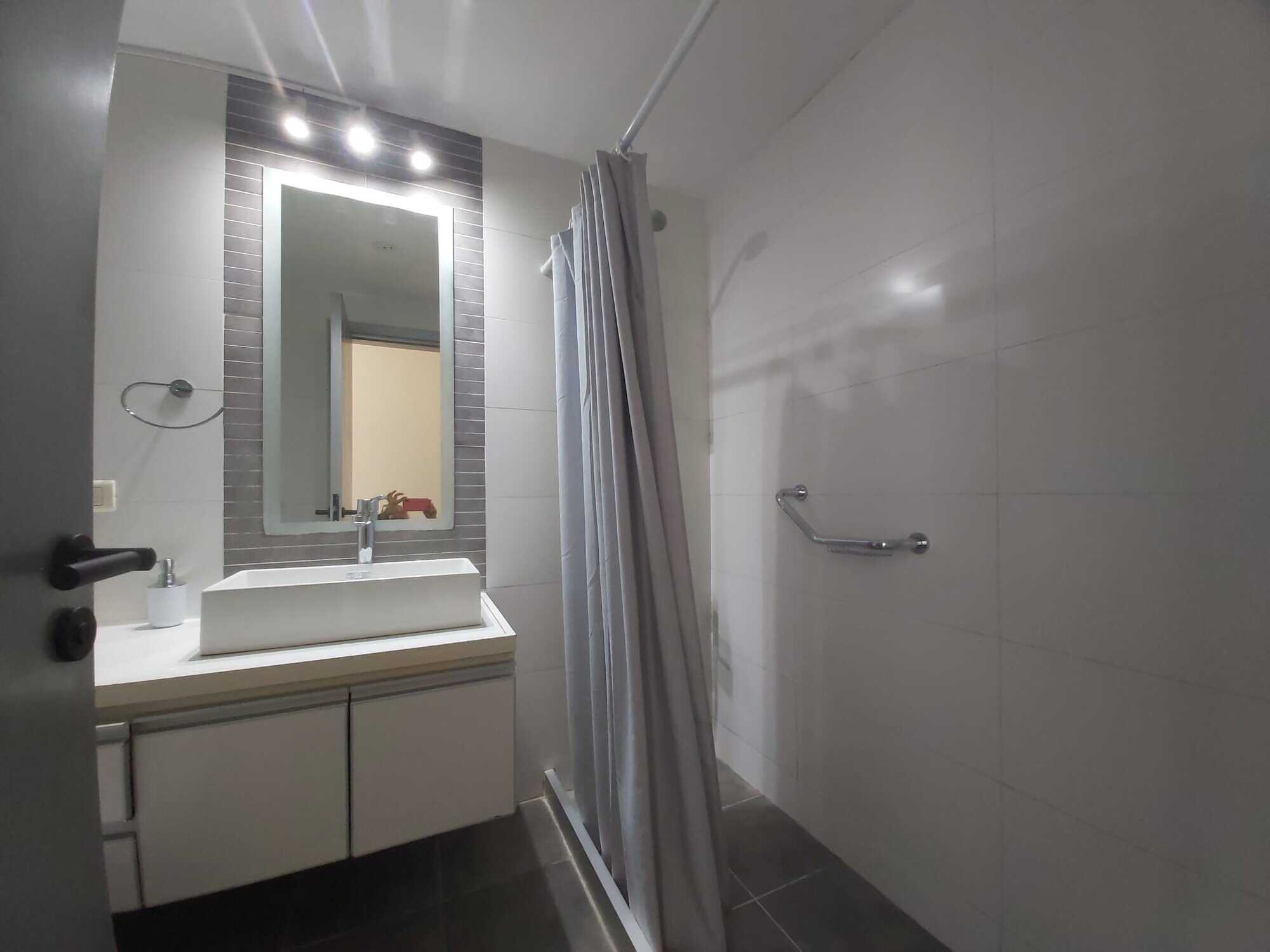 Bright bathroom with sink, mirror, and shower area in La Pastora, Punta del Este.