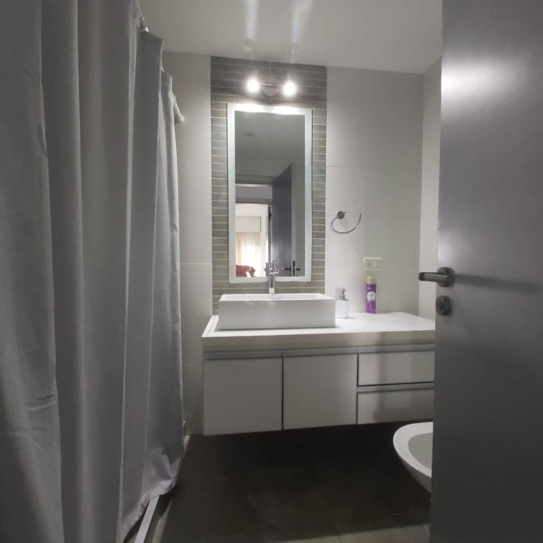 Bright bathroom featuring a sleek vanity, mirror, and shower curtain in La Pastora, Punta del Este.