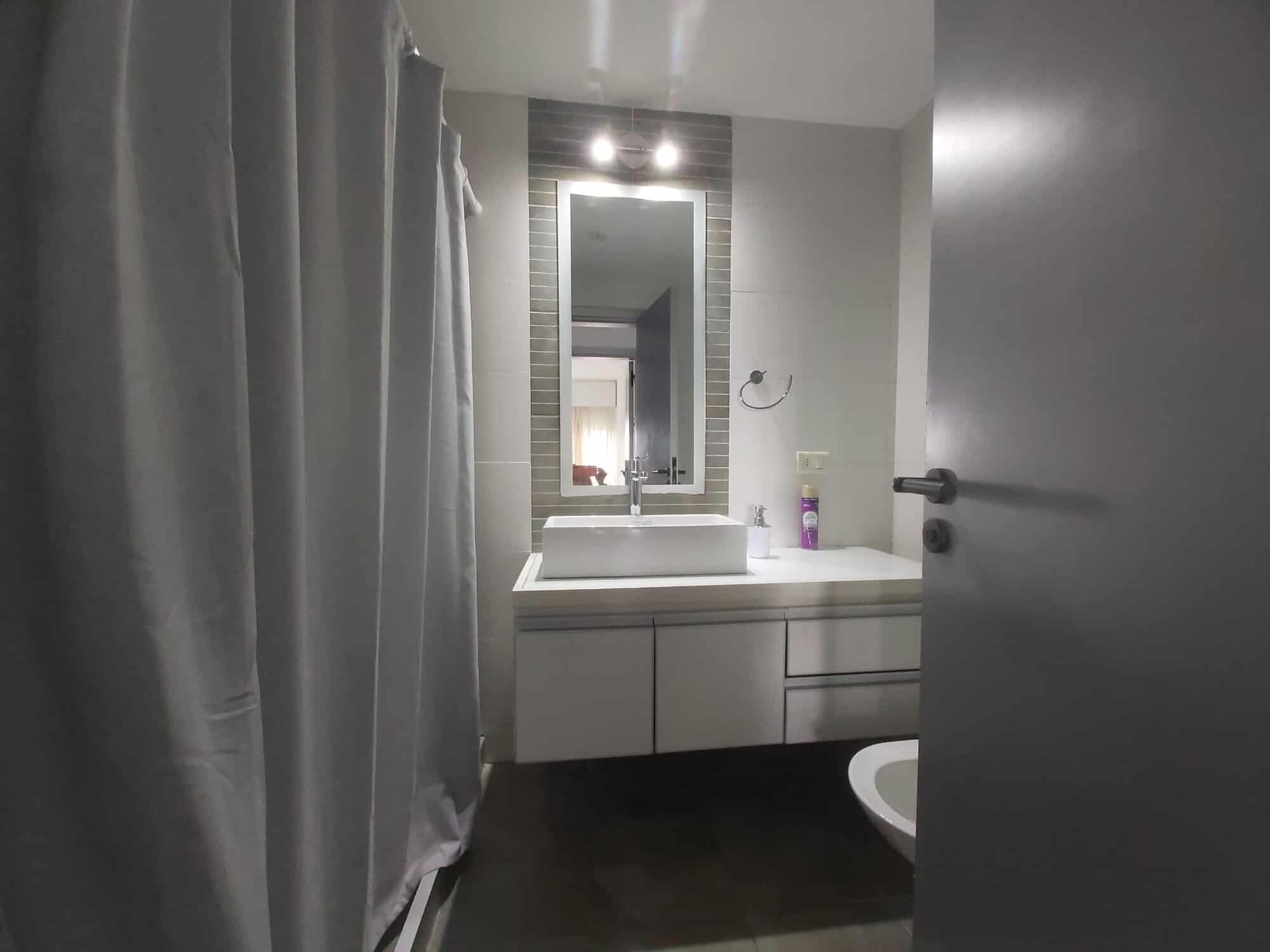 Bright bathroom featuring a sleek vanity, mirror, and shower curtain in La Pastora, Punta del Este.