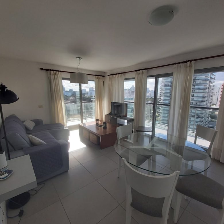 Bright apartment interior with large windows and balcony overlooking Punta del Este skyline.