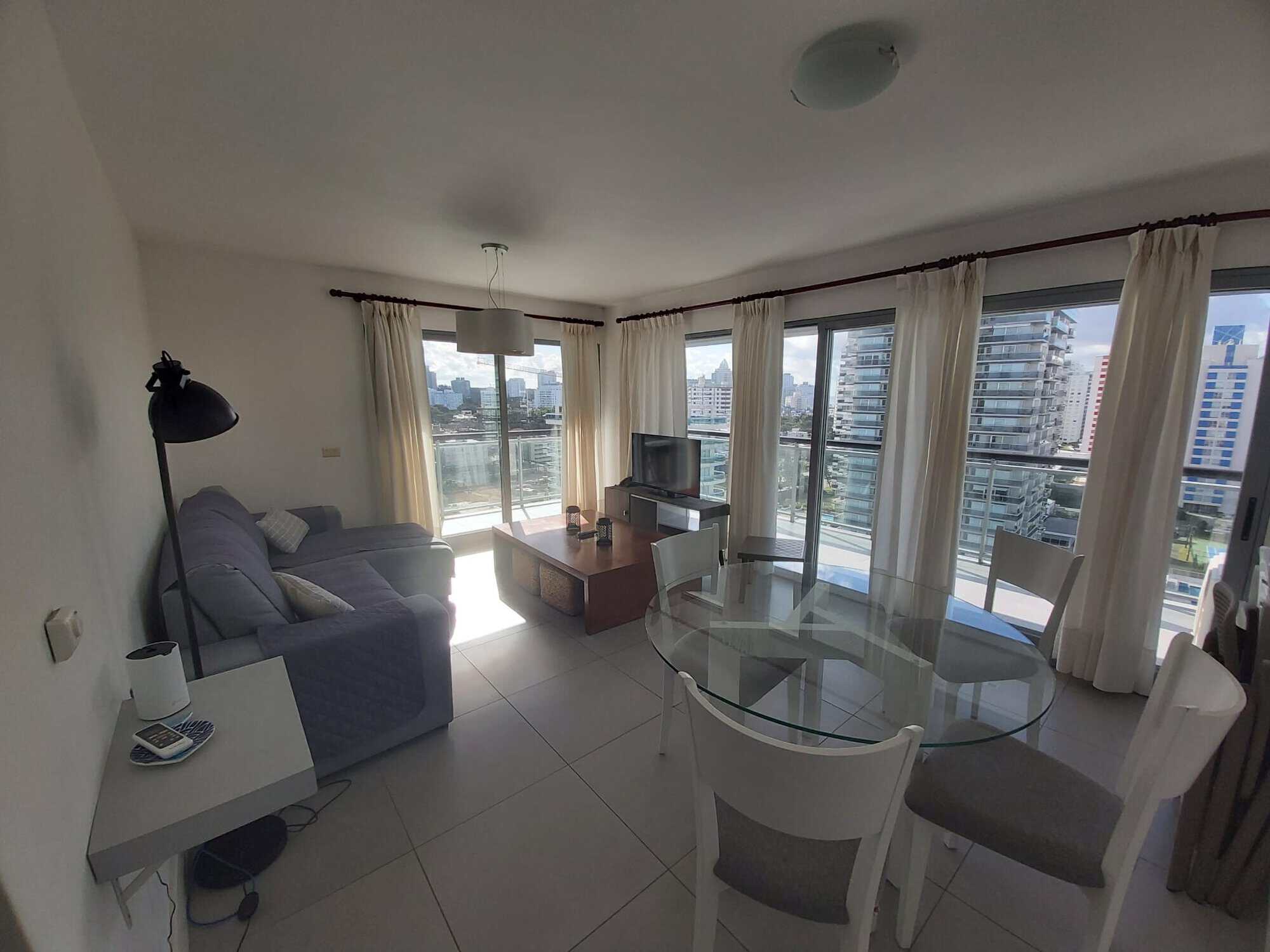 Bright apartment interior with large windows and balcony overlooking Punta del Este skyline.