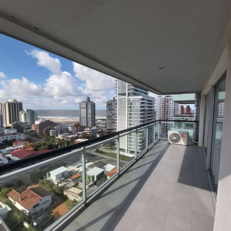 Balcony of a modern apartment in Punta del Este with city skyline and ocean in the background.