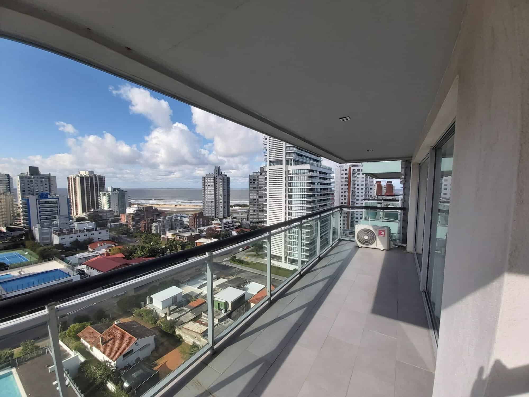 Balcony of a modern apartment in Punta del Este with city skyline and ocean in the background.