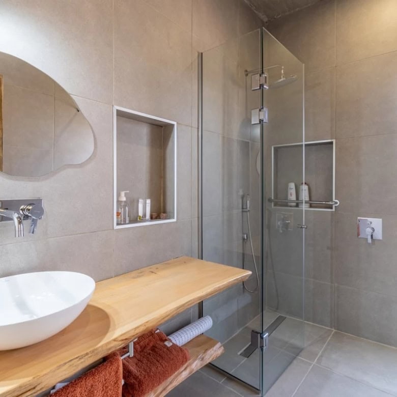 Contemporary bathroom featuring a walk-in shower, wooden vanity, and natural light.