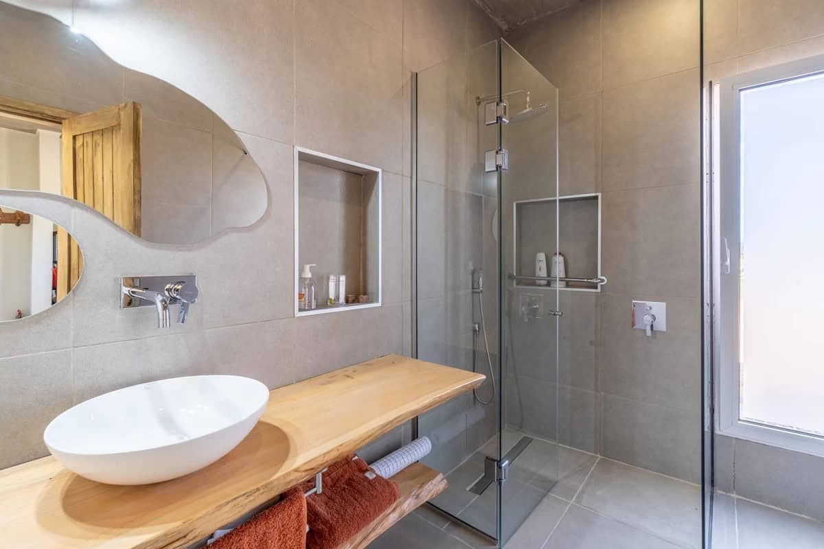 Contemporary bathroom featuring a walk-in shower, wooden vanity, and natural light.