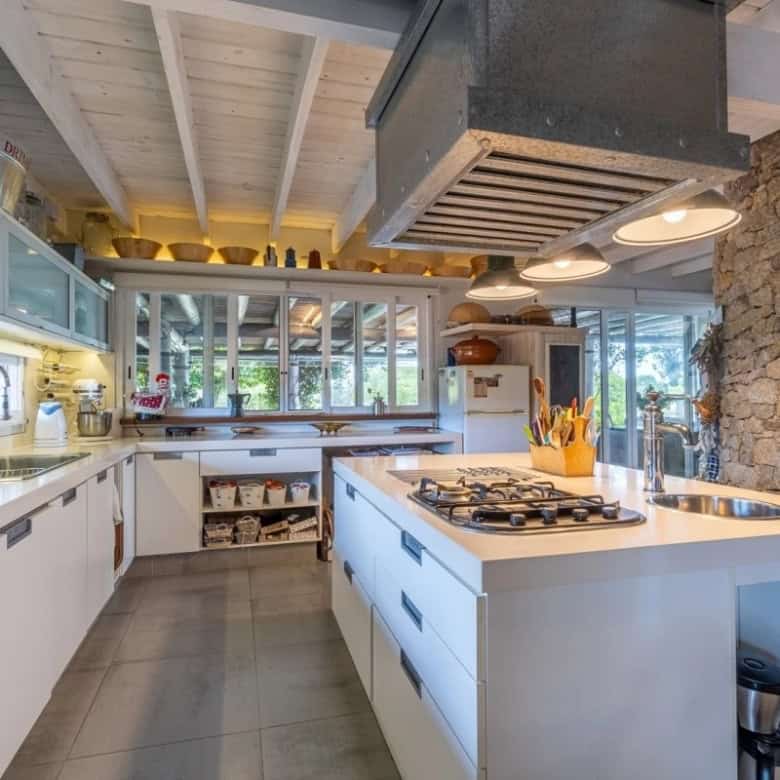 Modern country house kitchen with white cabinetry and stone accents in Punta Ballena.