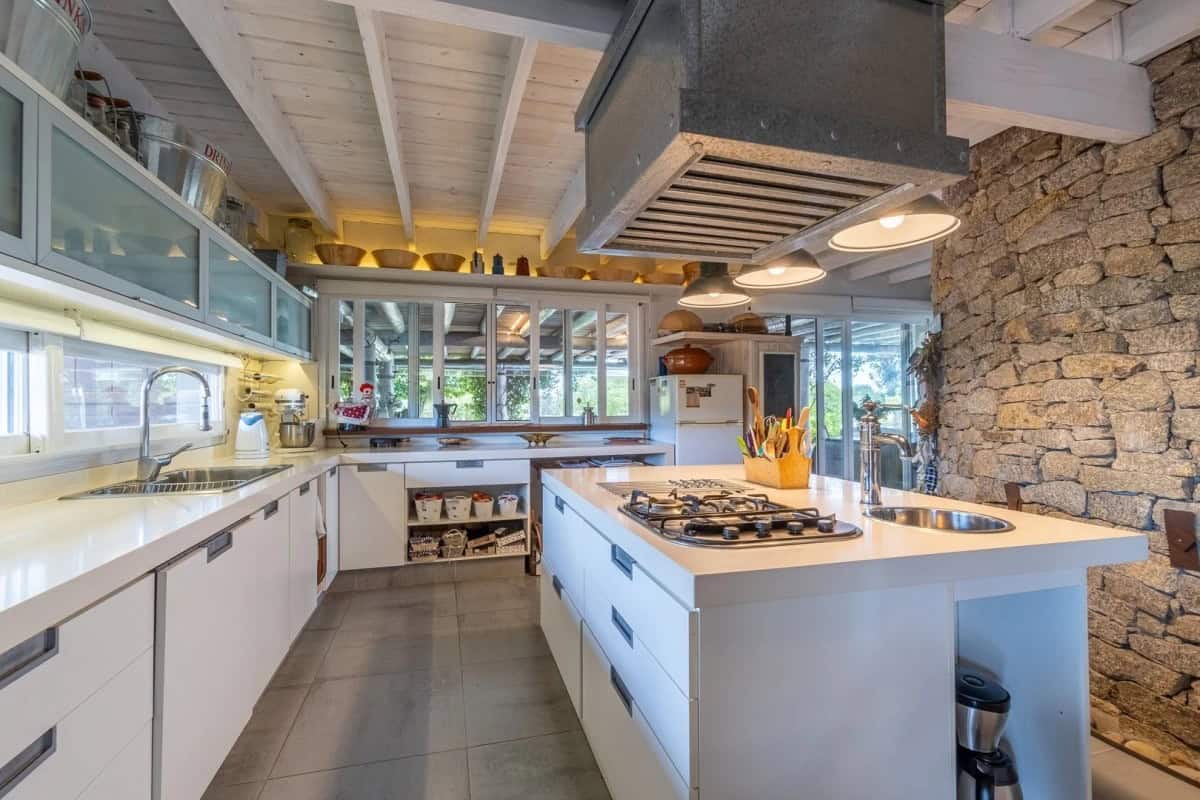 Modern country house kitchen with white cabinetry and stone accents in Punta Ballena.