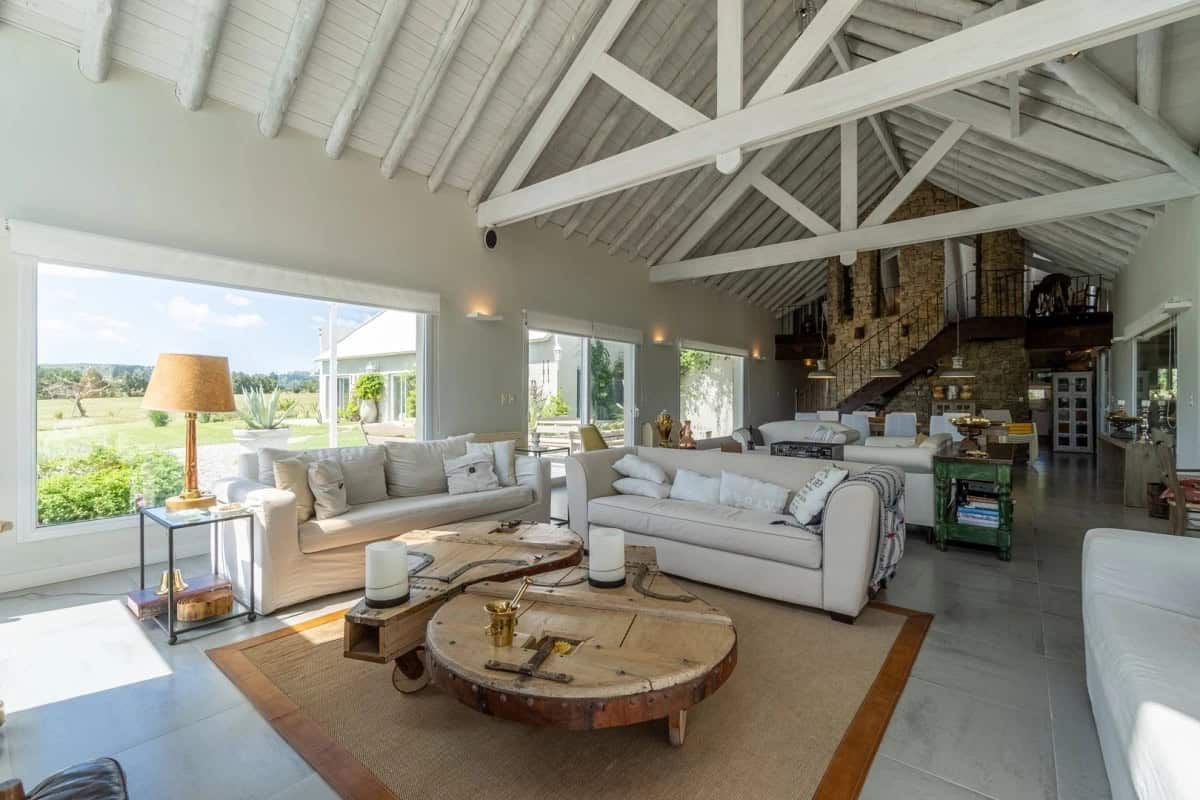 Spacious living room with large windows, high vaulted ceilings, and modern decor in Punta Ballena, M.