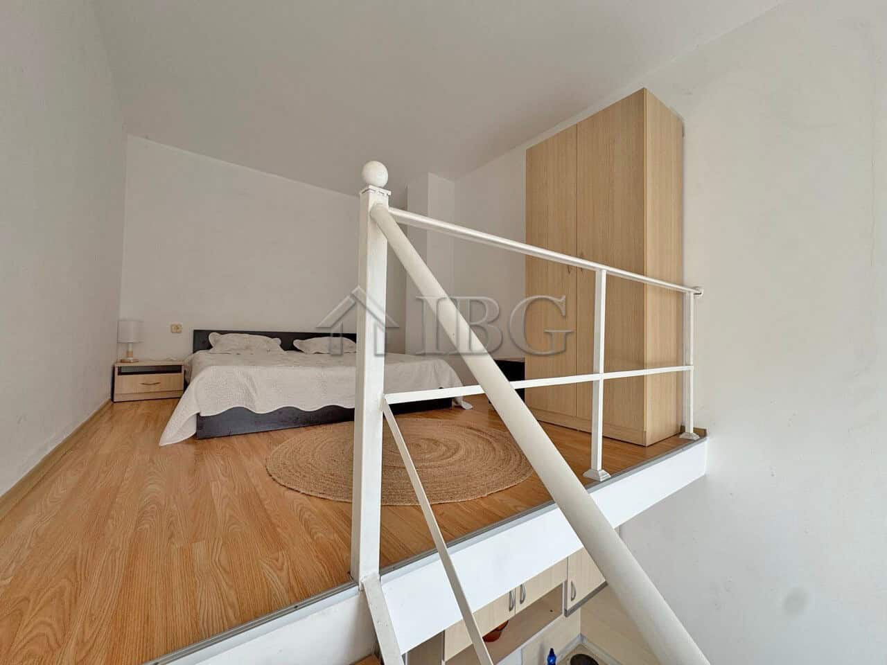 Bright duplex bedroom with white walls and wooden flooring.