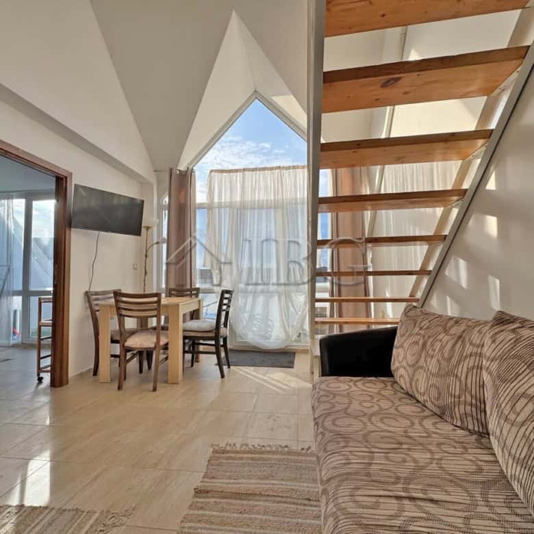 Spacious living area with modern furniture, large windows, and wooden staircase in Sunny Beach.