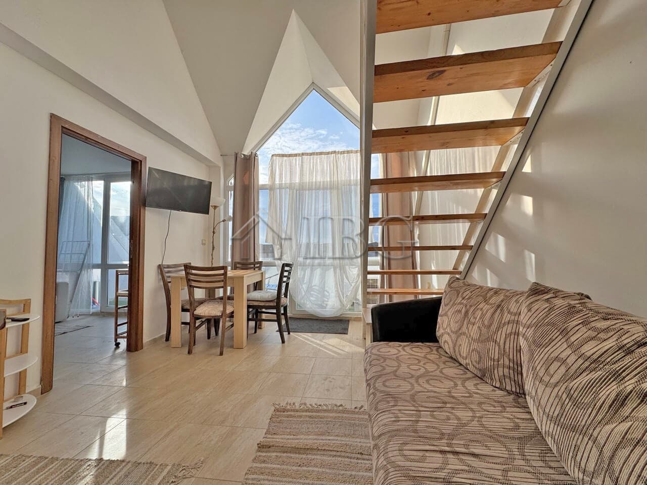Spacious living area with modern furniture, large windows, and wooden staircase in Sunny Beach.