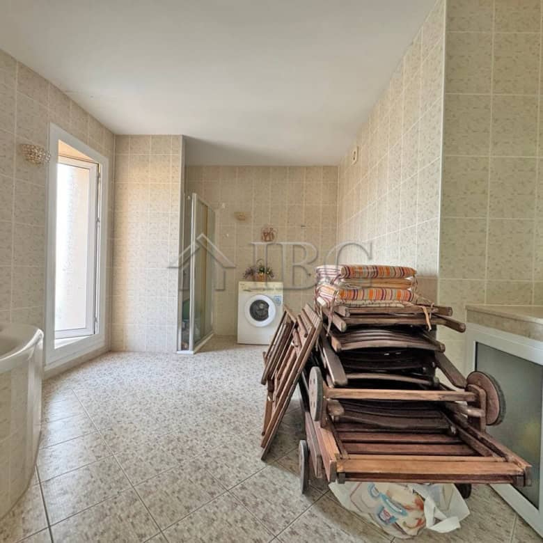 Bright bathroom with bathtub and laundry area in a beachfront apartment.