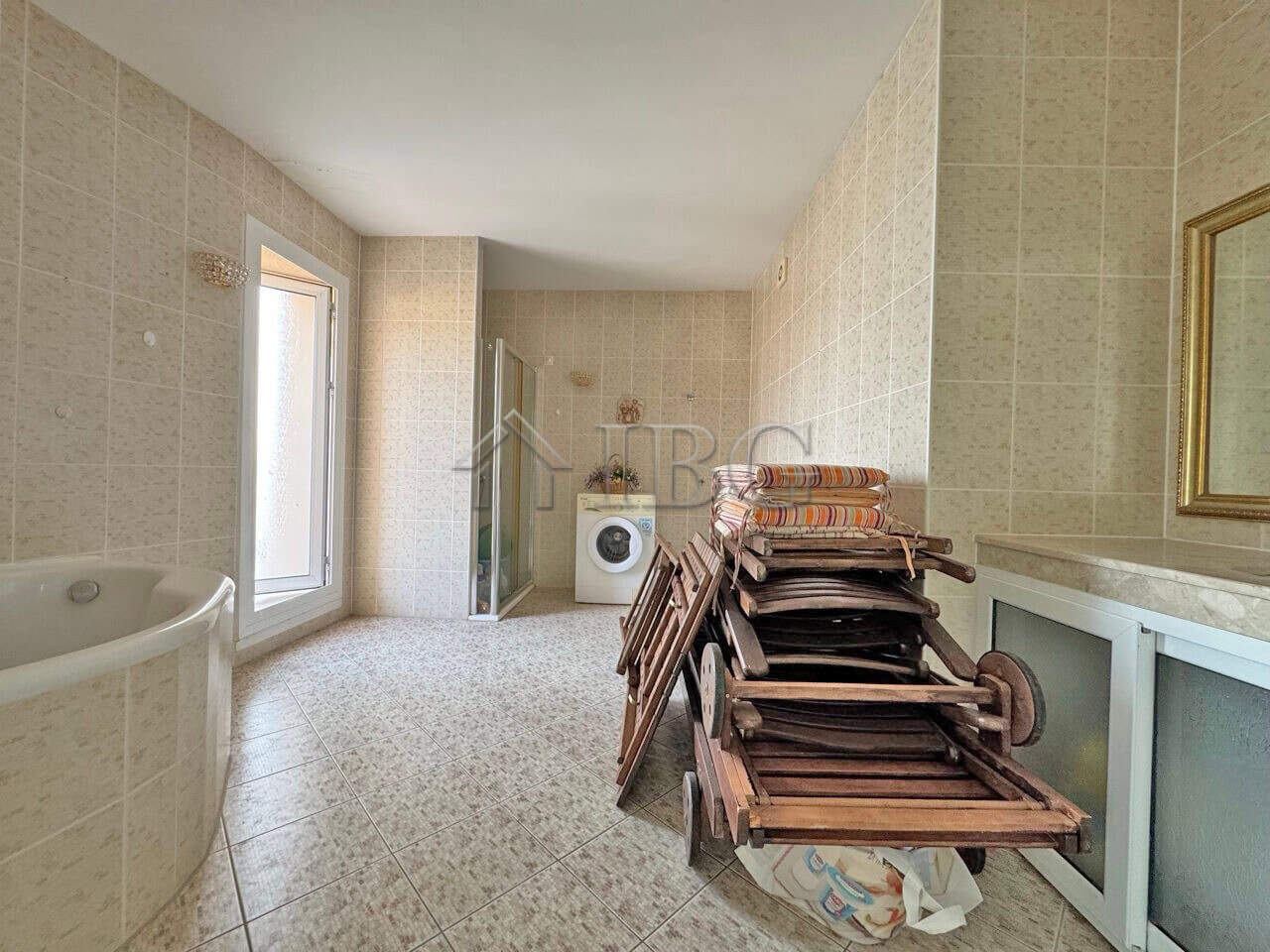 Bright bathroom with bathtub and laundry area in a beachfront apartment.