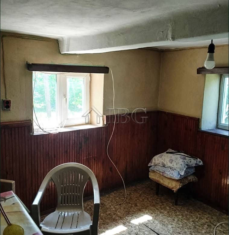 Interior of a rustic village house with wooden paneling and natural light from windows.