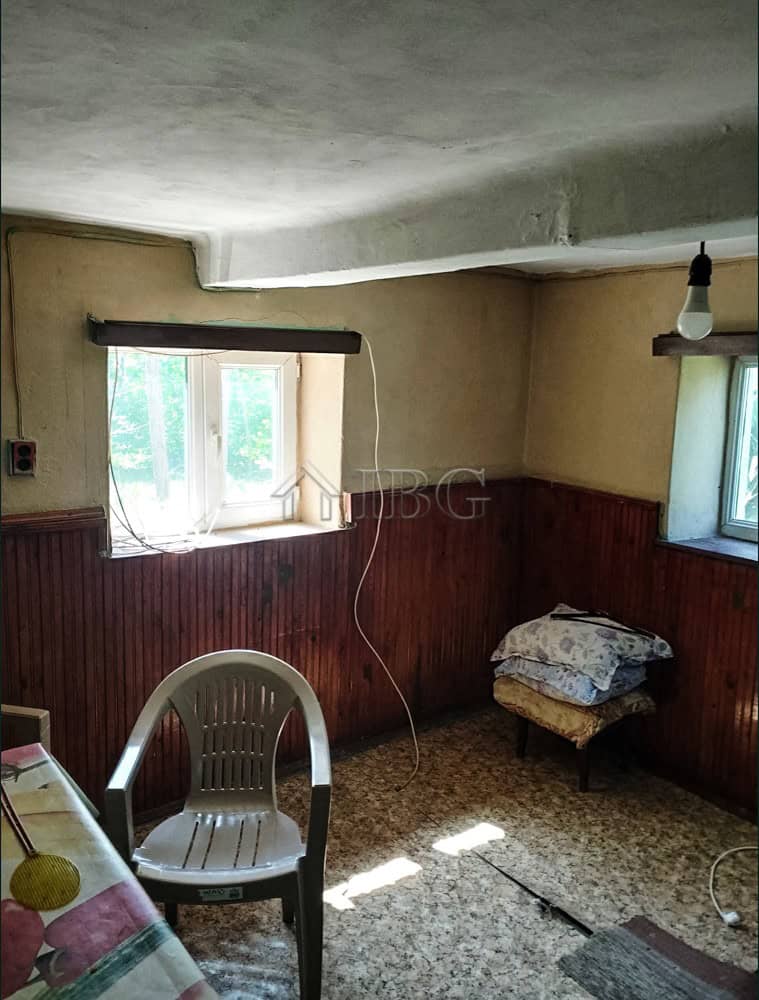 Interior of a rustic village house with wooden paneling and natural light from windows.