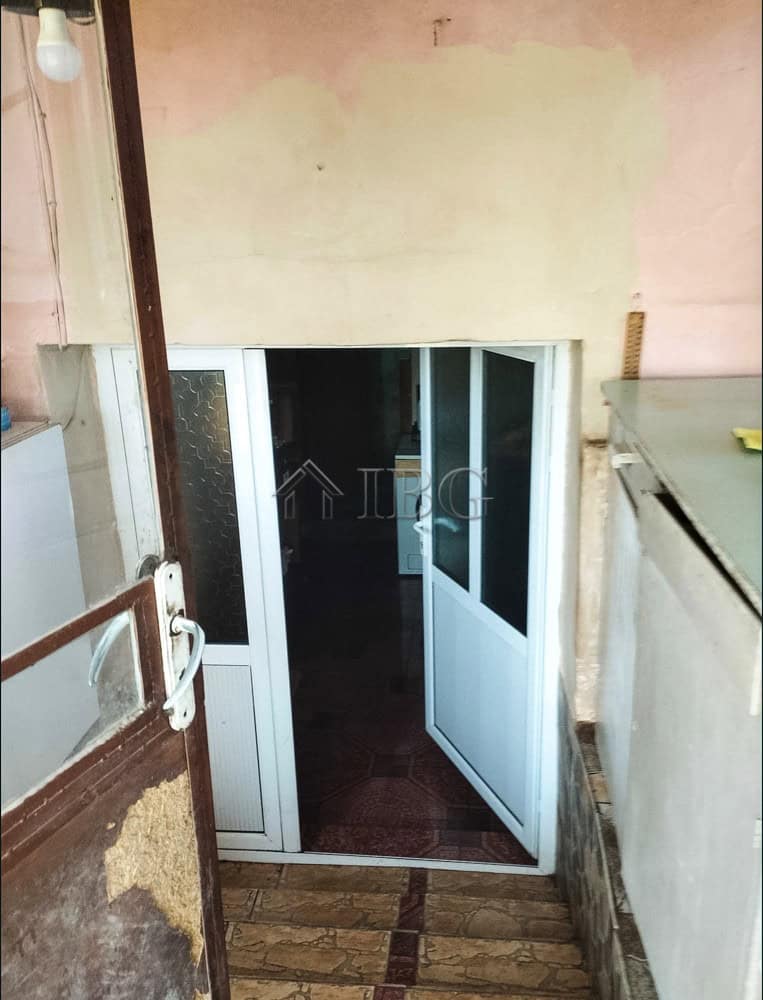 Modern glass door entrance to a two-storey house with garden view.