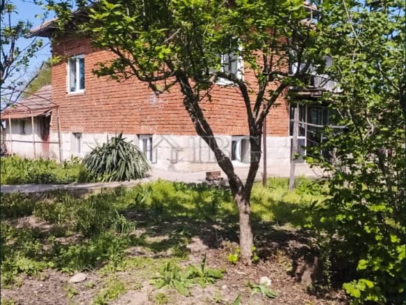 Elegant two-storey home with lush garden and mature trees in a peaceful village setting.