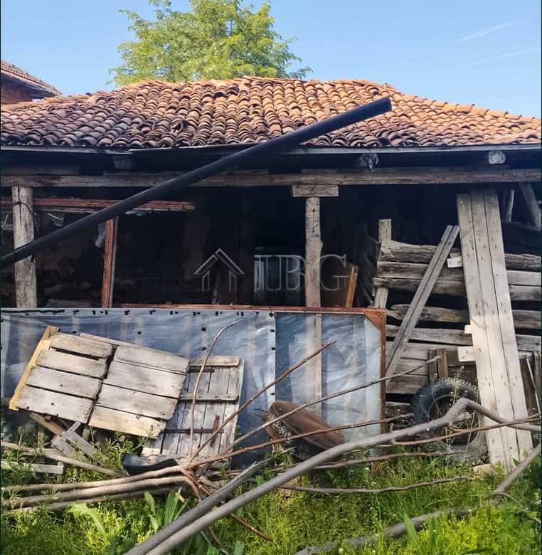 Old rustic house with garden and construction materials in a rural setting.