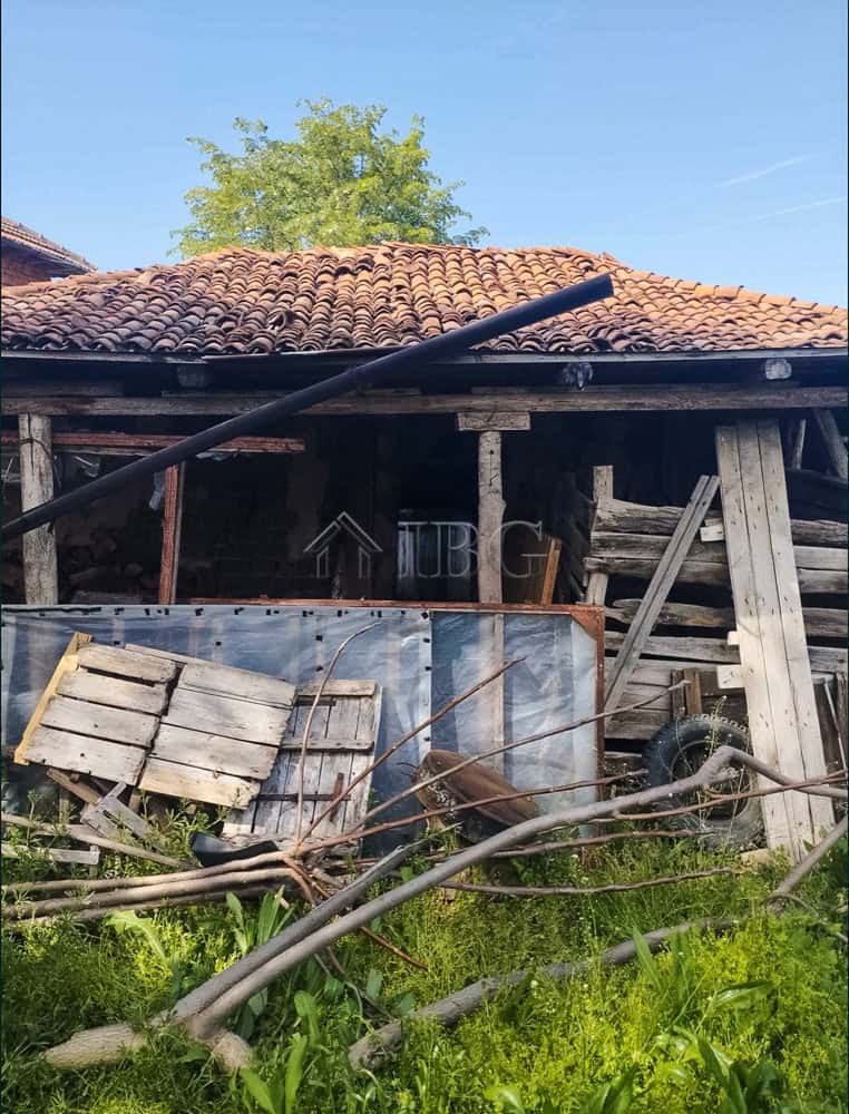 Old rustic house with garden and construction materials in a rural setting.