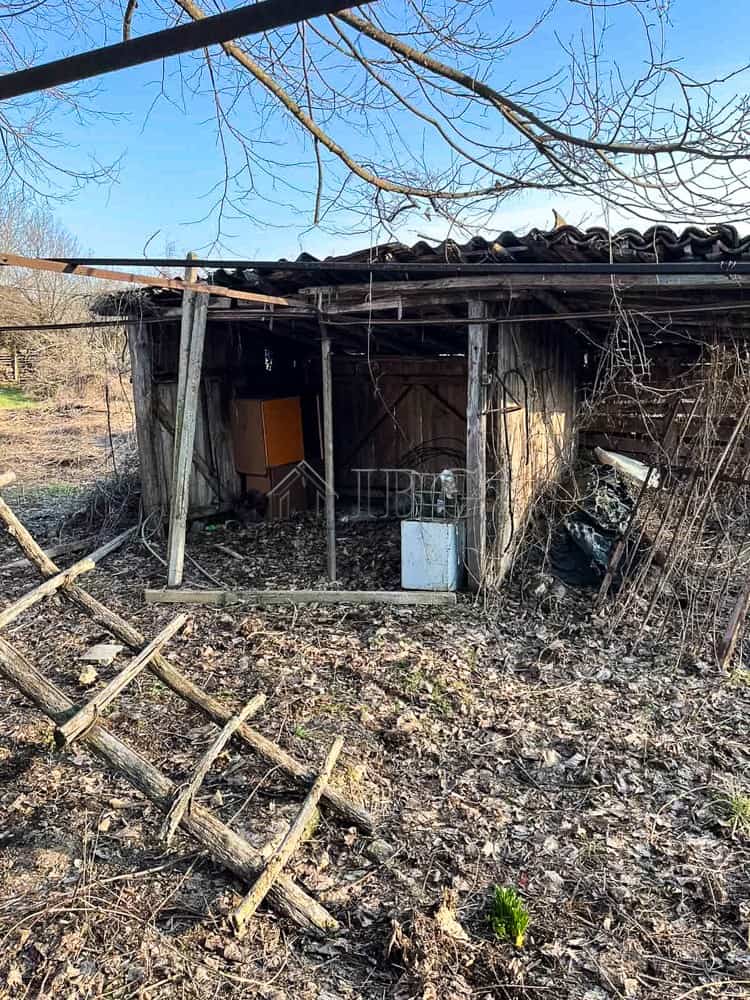 House at the Edge of Brestovitsa Village, Ruse Area – Large Garden, Garage and Outbuildings Old wooden shed with a tiled roof, surrounded by a large garden and trees in a rural setting.