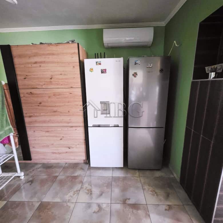 Spacious kitchen featuring two refrigerators against a green wall, ideal for family living close to.