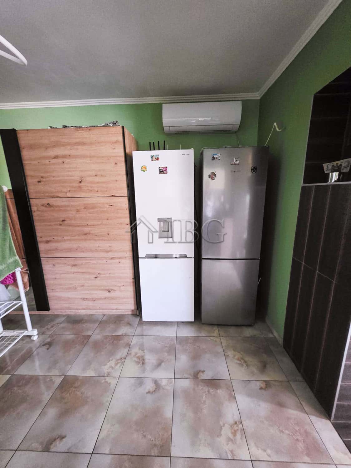 Spacious kitchen featuring two refrigerators against a green wall, ideal for family living close to.
