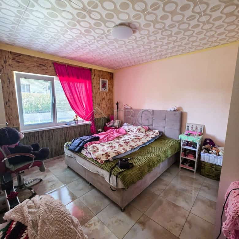 Bright bedroom with large window, pink curtains, and a comfortable bed.