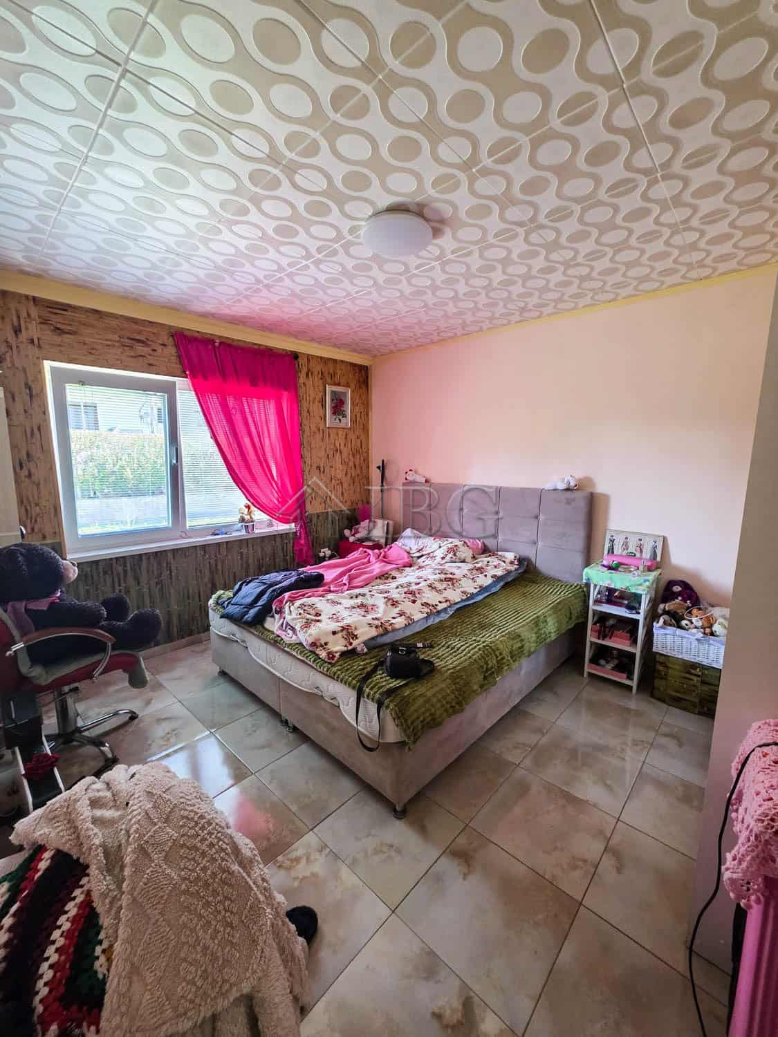Bright bedroom with large window, pink curtains, and a comfortable bed.