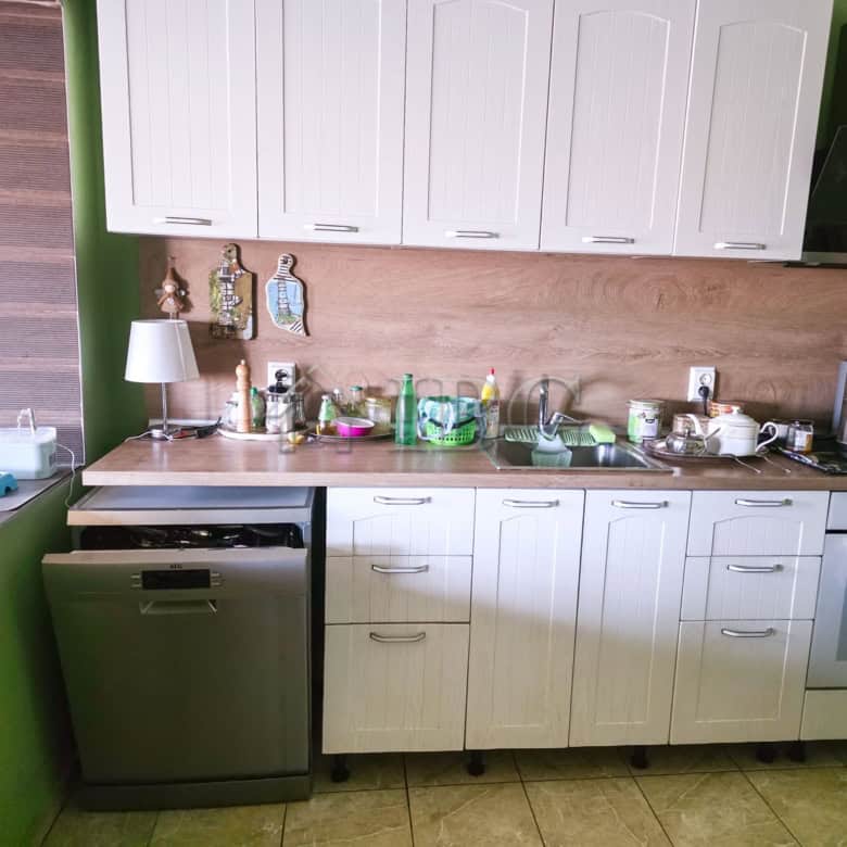 Bright kitchen featuring white cabinets, green walls, and essential appliances including a dishwashe.