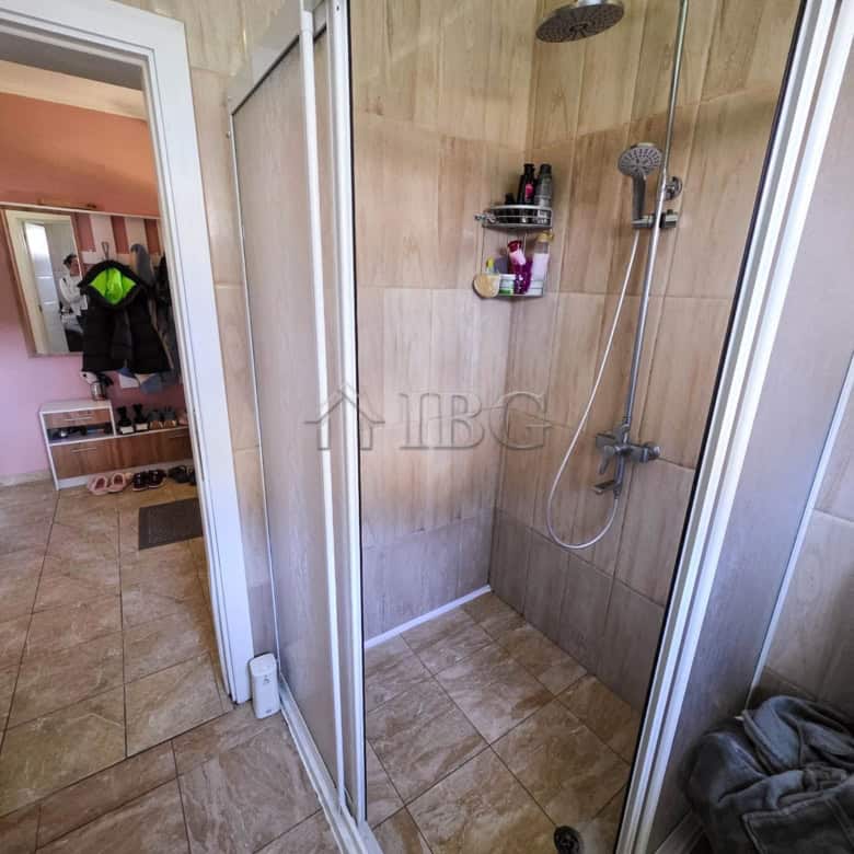 Bathroom shower area with modern fixtures and beige tiled walls.