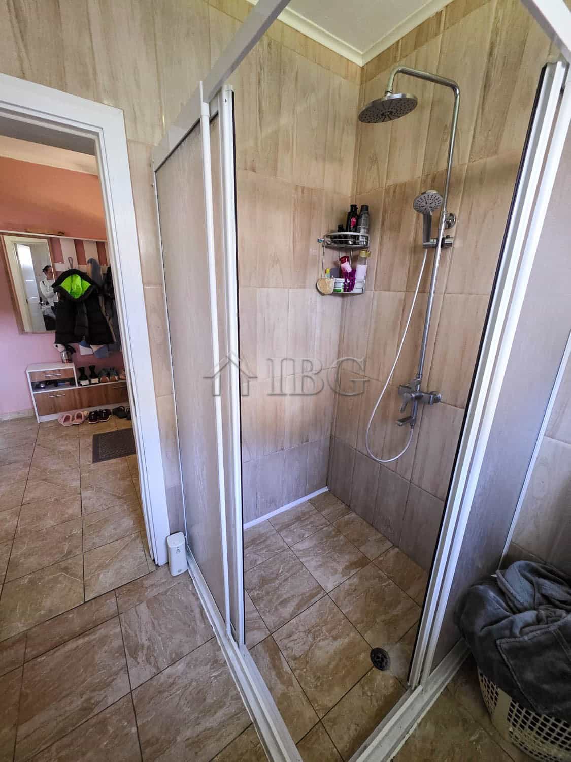 Bathroom shower area with modern fixtures and beige tiled walls.