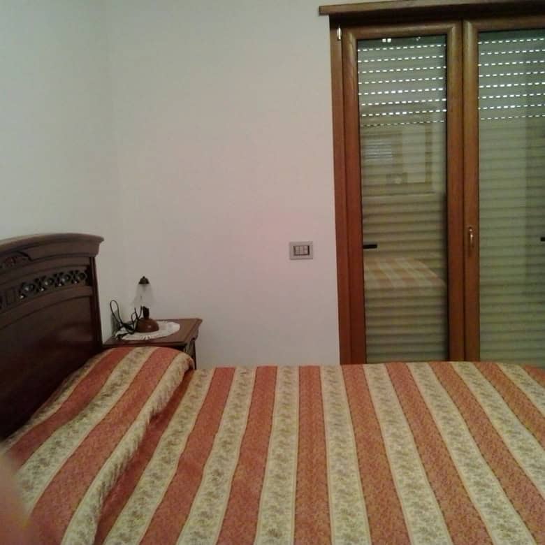 House interior with double bed and wooden furniture in Orsara di Puglia, Italy.