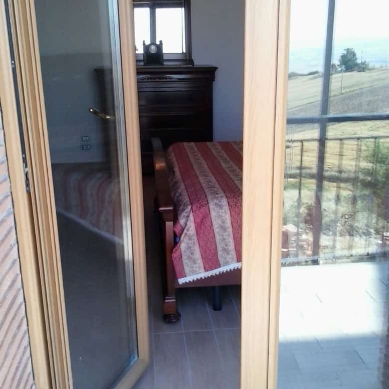Cozy bedroom with traditional furniture and scenic balcony view in Orsara di Puglia.