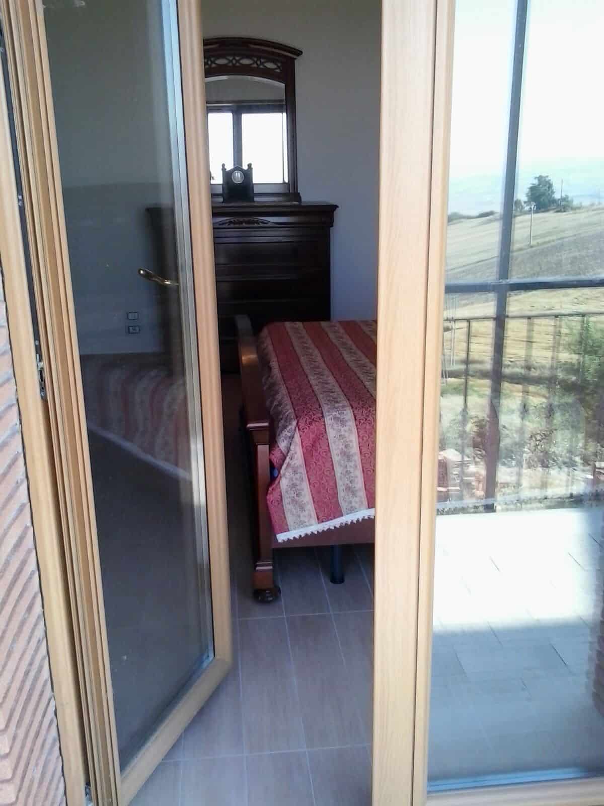 Cozy bedroom with traditional furniture and scenic balcony view in Orsara di Puglia.